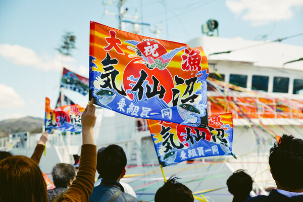 船へとつながる紙テープと大漁旗で漁港はカラフルに