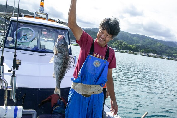 魚を釣り上げて嬉しそうな本藤さん