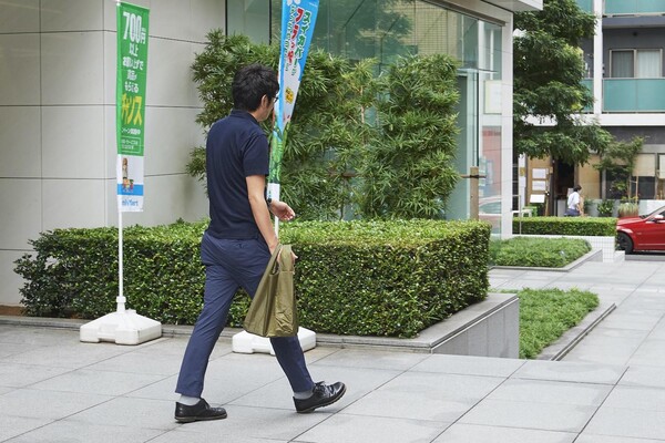 コンビニからレジ袋を下げて出る人