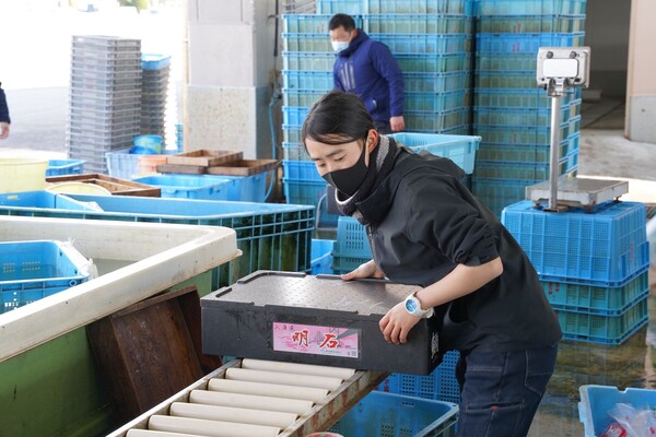 魚を運ぶ女性職員